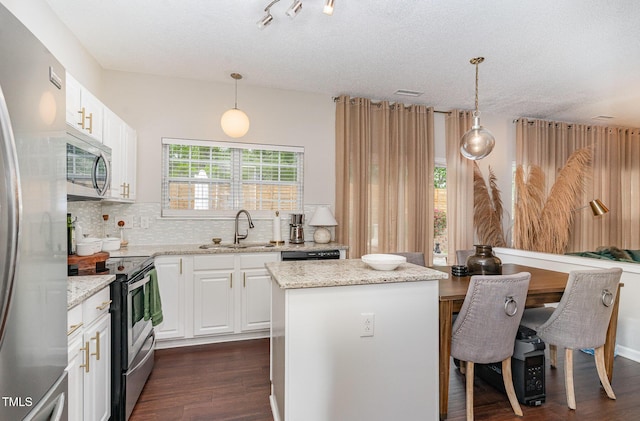 kitchen with stainless steel appliances, backsplash, a sink, dark wood-type flooring, and a kitchen island