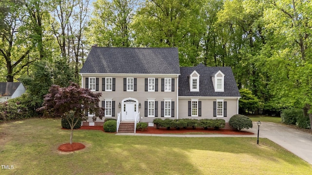 colonial home with crawl space, driveway, a shingled roof, and a front yard