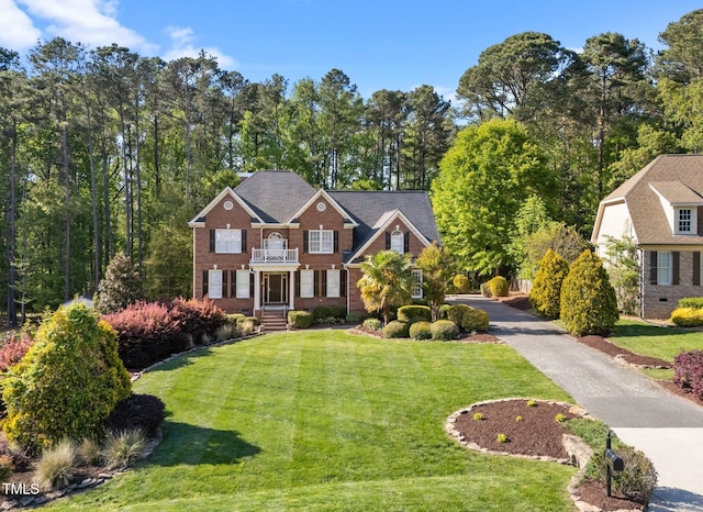 view of front of home featuring a front lawn, a balcony, and brick siding