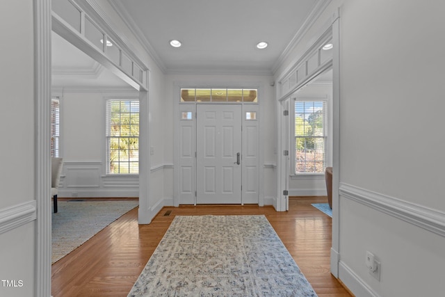 foyer entrance with crown molding, a wainscoted wall, wood finished floors, and recessed lighting
