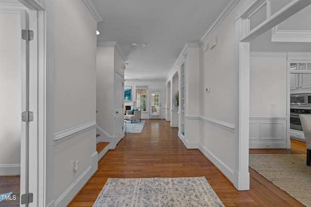 corridor with wood finished floors and crown molding