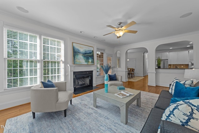 living room with arched walkways, a healthy amount of sunlight, and light wood-style floors