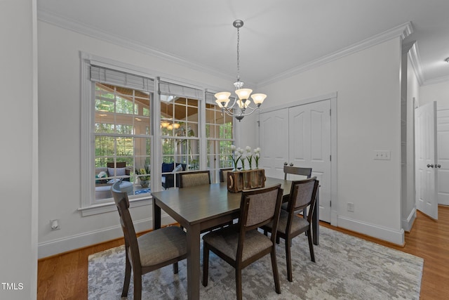 dining area featuring wood finished floors, baseboards, a chandelier, and crown molding