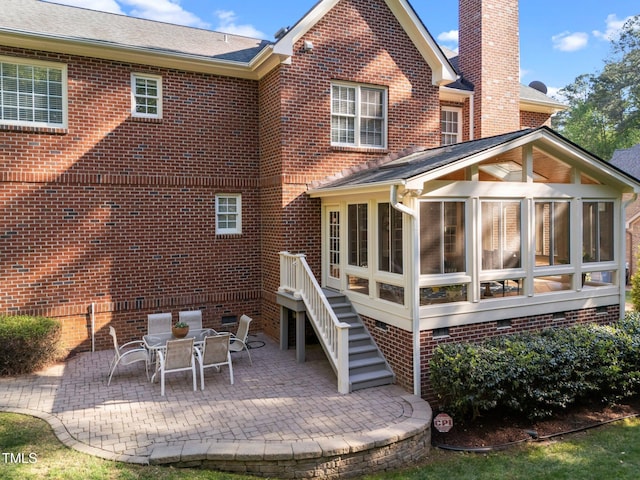 rear view of house featuring a chimney, a patio area, crawl space, brick siding, and a sunroom