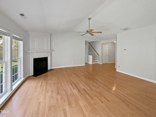 107 Kinship Ln, Apex, NC 27502 - unfurnished living room with stairs, light wood-style floors, a fireplace with flush hearth, ceiling fan, and visible vents