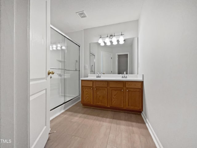 107 Kinship Ln, Apex, NC 27502 - bathroom featuring a sink, double vanity, visible vents, wood finished floors, and a shower stall