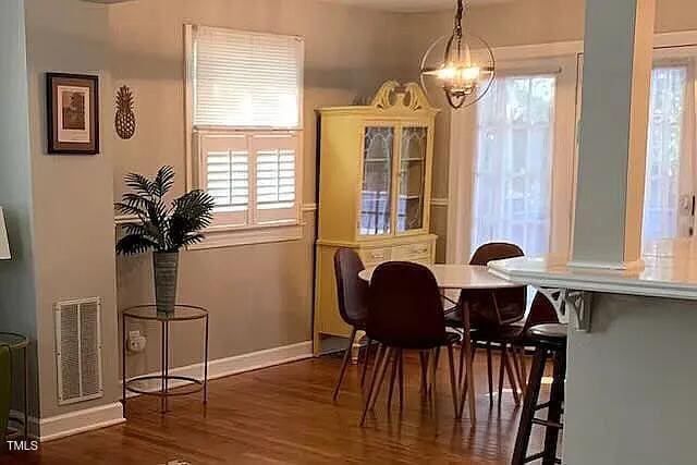 dining space featuring baseboards, a healthy amount of sunlight, wood finished floors, and visible vents