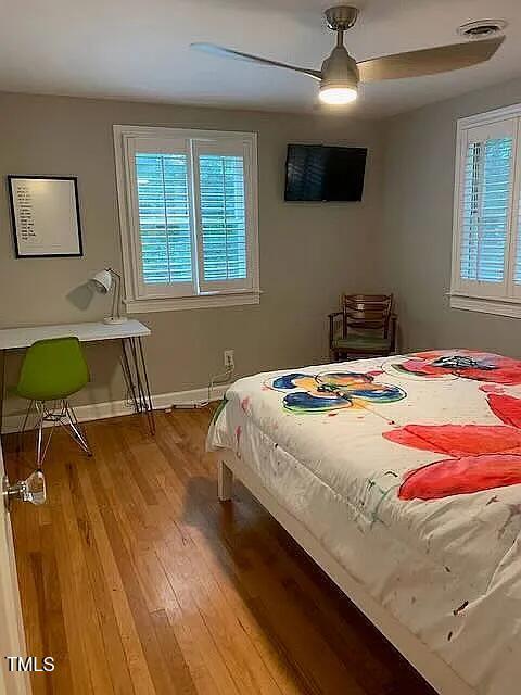 bedroom featuring visible vents, baseboards, wood finished floors, and multiple windows