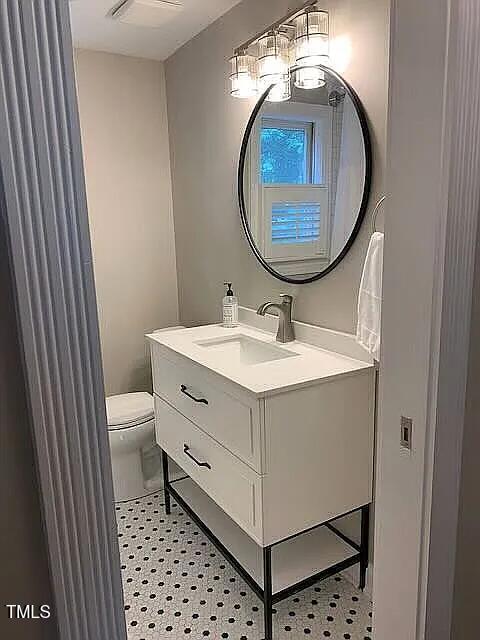 half bath with toilet, vanity, and tile patterned floors