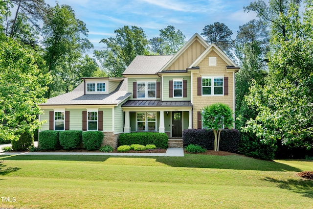 craftsman-style house featuring covered porch, board and batten siding, a standing seam roof, roof with shingles, and a front lawn