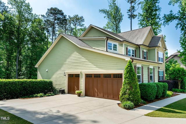 view of property exterior featuring a garage, a shingled roof, and driveway