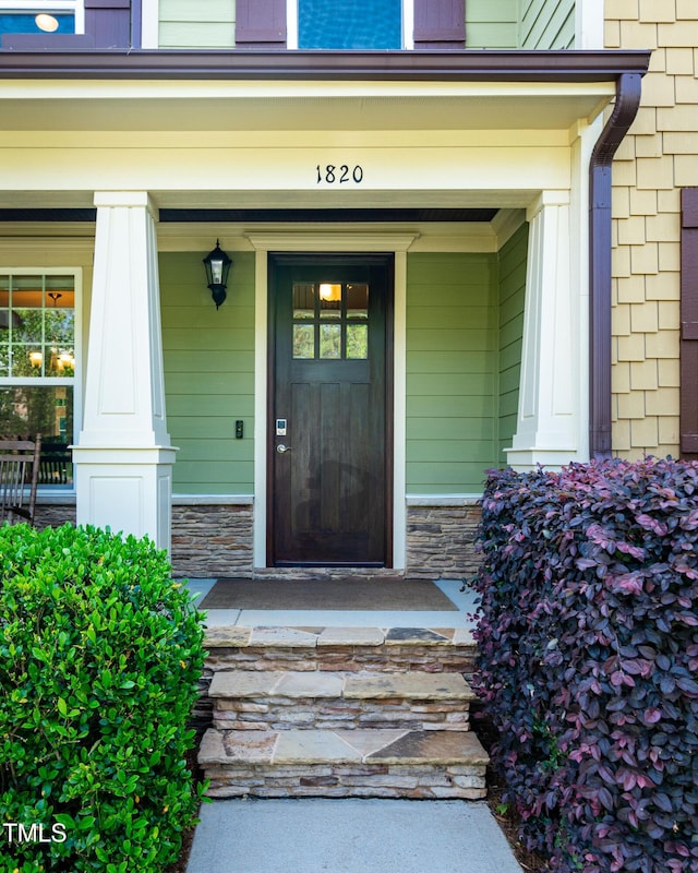 view of exterior entry featuring a porch and stone siding