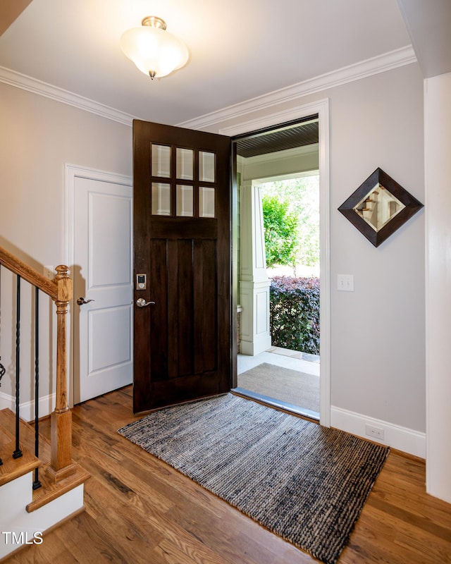 foyer entrance featuring ornamental molding, stairs, and wood finished floors