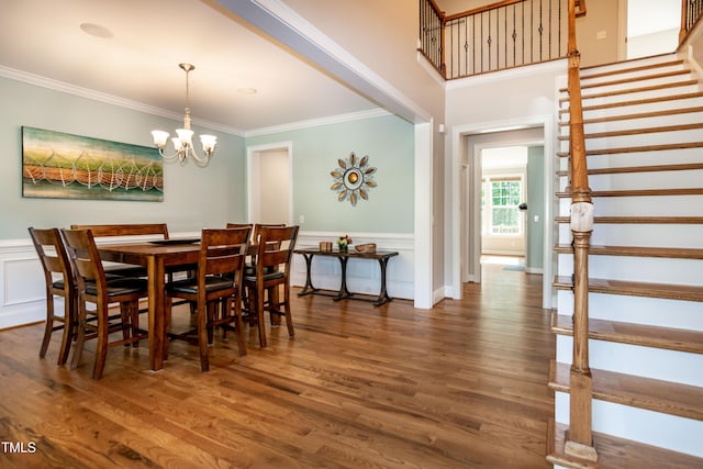 dining room featuring crown molding, stairs, wood finished floors, a wainscoted wall, and a chandelier