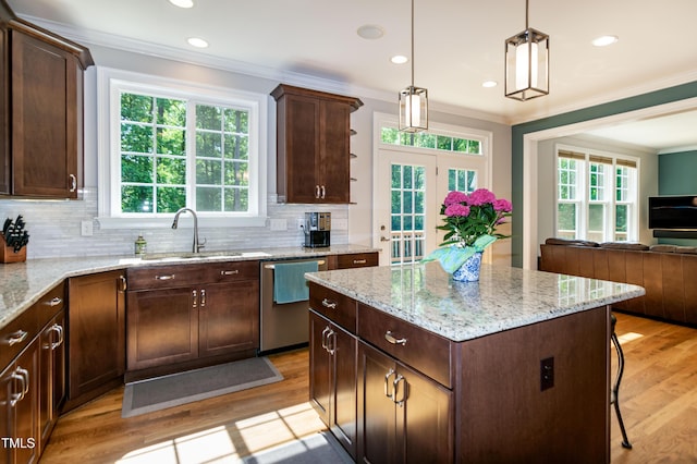kitchen featuring backsplash, crown molding, stainless steel dishwasher, a sink, and open floor plan