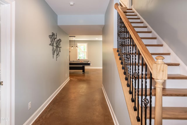 hall featuring baseboards, concrete floors, and stairway