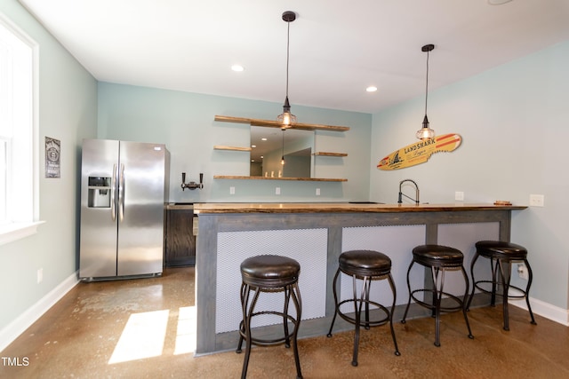 kitchen featuring stainless steel fridge, baseboards, open shelves, and a breakfast bar