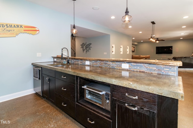 kitchen with a sink, recessed lighting, baseboards, open floor plan, and stainless steel dishwasher
