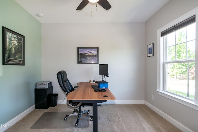 carpeted office space featuring baseboards, a ceiling fan, and a healthy amount of sunlight