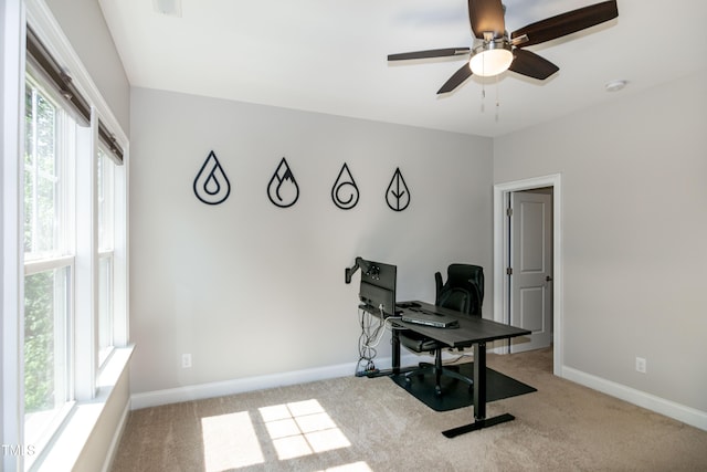 carpeted office space featuring ceiling fan and baseboards