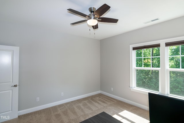 empty room with a ceiling fan, baseboards, visible vents, and light carpet
