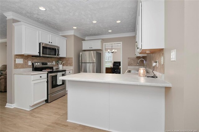 119 Woodbine Dr, Raeford, NC 28376 - kitchen with appliances with stainless steel finishes, a sink, a peninsula, white cabinetry, and crown molding