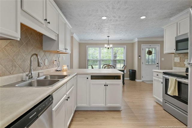 119 Woodbine Dr, Raeford, NC 28376 - kitchen featuring stainless steel appliances, ornamental molding, a sink, light wood-type flooring, and a peninsula