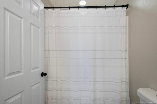 119 Woodbine Dr, Raeford, NC 28376 - bathroom featuring a textured ceiling, toilet, and a shower with shower curtain
