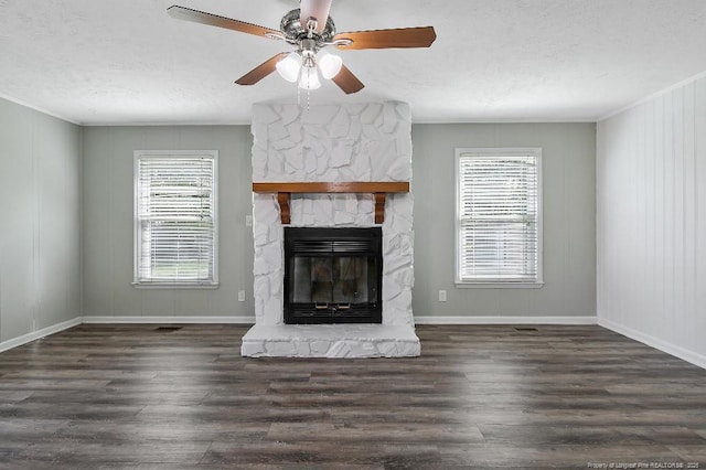 unfurnished living room with baseboards, wood finished floors, a stone fireplace, and a textured ceiling