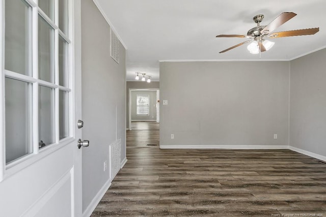 unfurnished room featuring dark wood-style floors, visible vents, ornamental molding, baseboards, and ceiling fan