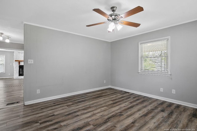 spare room with baseboards, ornamental molding, dark wood-type flooring, and plenty of natural light