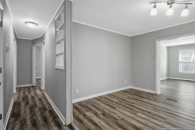 corridor featuring dark wood-type flooring, visible vents, baseboards, and ornamental molding