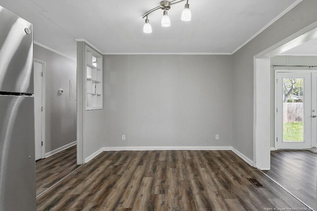 unfurnished dining area featuring dark wood-style floors, baseboards, crown molding, and visible vents