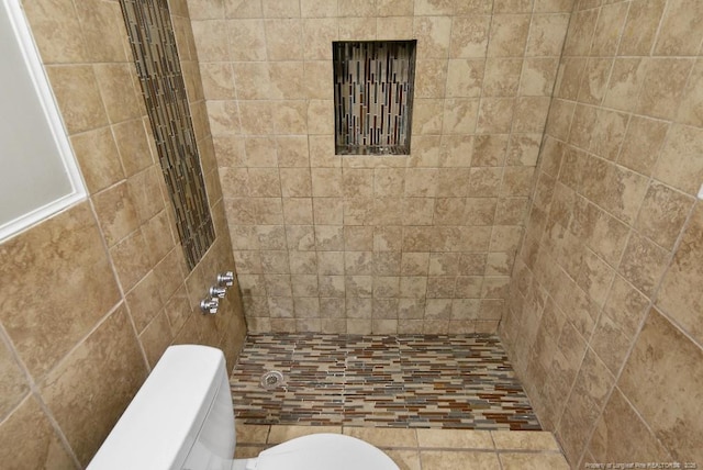 full bathroom with a tile shower and toilet