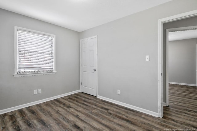 unfurnished bedroom featuring baseboards and dark wood-type flooring