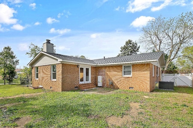 back of house with a gate, fence, brick siding, a lawn, and crawl space