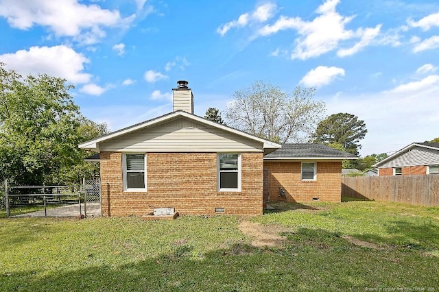 rear view of property with fence, crawl space, a lawn, and a chimney