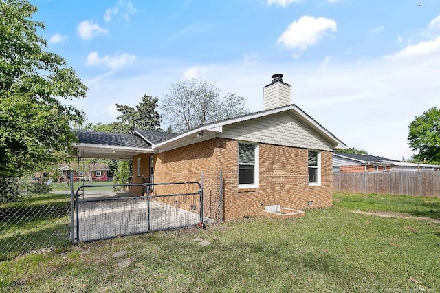 view of side of home featuring a lawn, a chimney, fence private yard, an attached carport, and brick siding