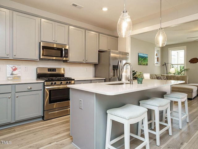 kitchen featuring gray cabinets, stainless steel appliances, visible vents, and a sink
