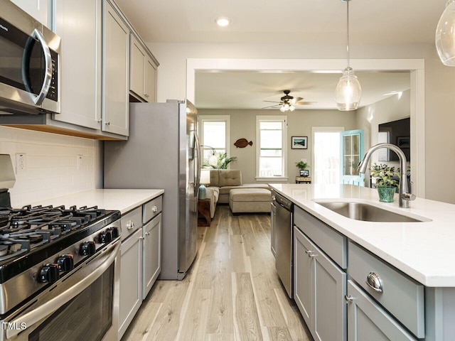 kitchen with a sink, stainless steel appliances, and gray cabinetry