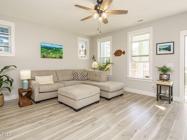 living room with visible vents, light wood finished floors, baseboards, and a ceiling fan