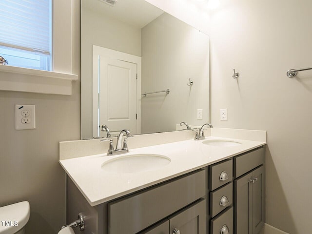 bathroom featuring a sink, double vanity, and toilet