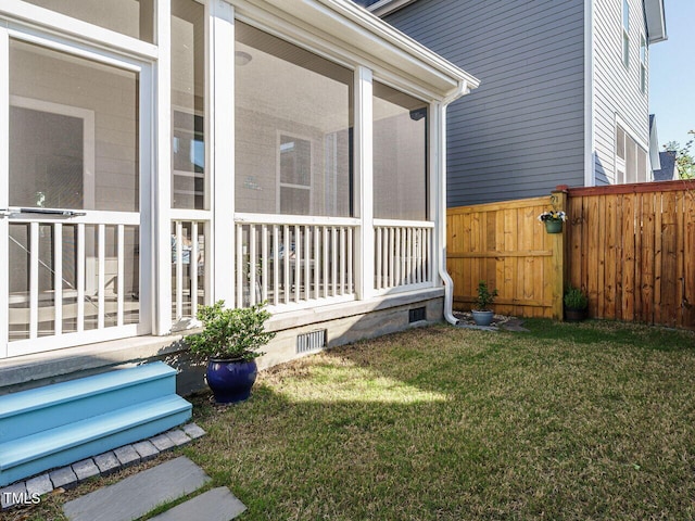 view of side of property with a lawn, crawl space, a sunroom, and a fenced backyard