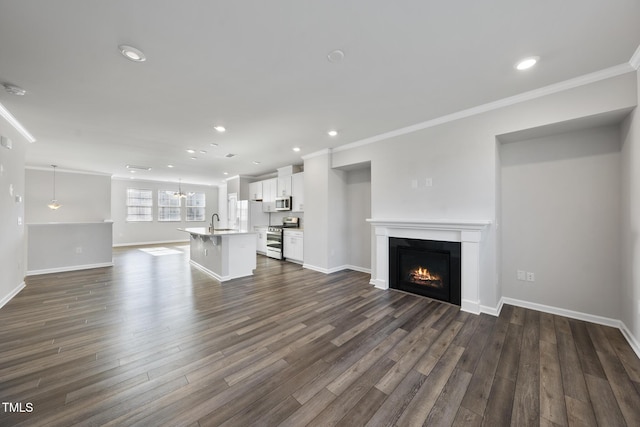 unfurnished living room featuring dark wood finished floors, baseboards, recessed lighting, crown molding, and a lit fireplace