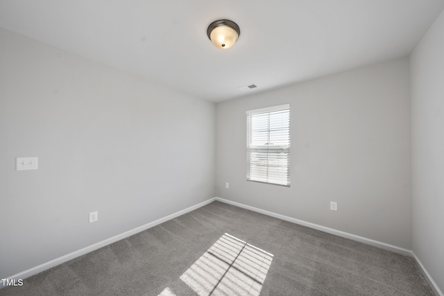 empty room featuring carpet floors, visible vents, and baseboards