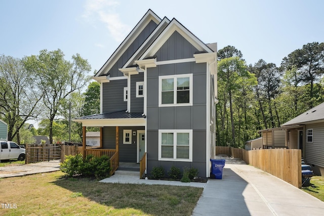 view of front of house featuring concrete driveway, board and batten siding, a standing seam roof, a porch, and metal roof