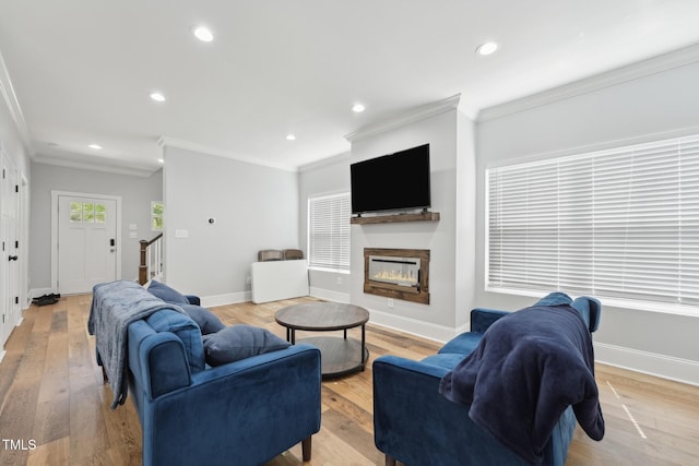 living area with a glass covered fireplace, recessed lighting, stairs, and ornamental molding