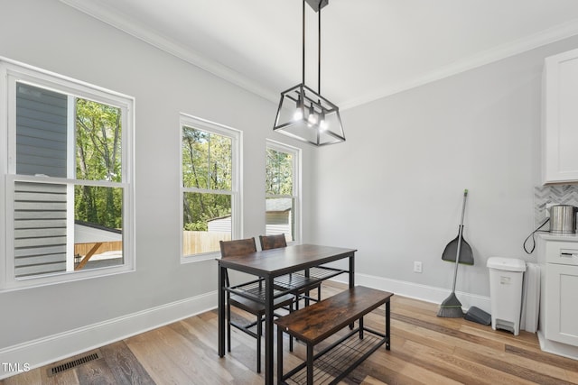 dining area with a wealth of natural light, a notable chandelier, crown molding, and visible vents