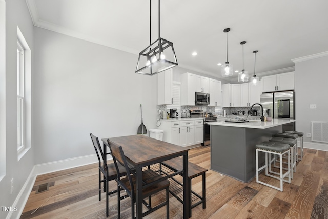 kitchen with a sink, tasteful backsplash, visible vents, crown molding, and appliances with stainless steel finishes
