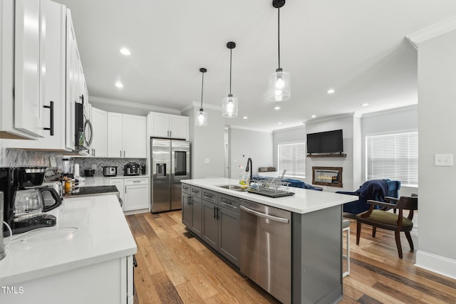 kitchen with a glass covered fireplace, a sink, appliances with stainless steel finishes, and crown molding